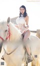 A woman riding on the back of a white horse.