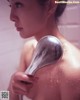 A woman taking a shower with a shower head.