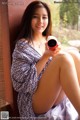 A woman sitting on a window sill holding a cup of coffee.