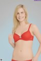 A woman in a red bra and panties posing for a picture.