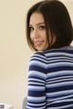 A woman in a blue and white striped shirt smiles at the camera.