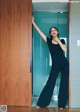 A woman in a black jumpsuit standing in front of a door.