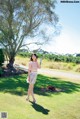 A woman standing in the grass talking on a cell phone.