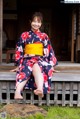 A woman in a kimono sitting on a wooden bench.