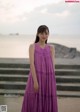 A woman in a purple dress standing on some steps.