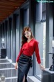 A woman in a red shirt and black skirt posing for a picture.