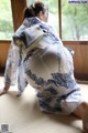 A woman in a blue and white kimono sitting on the floor.